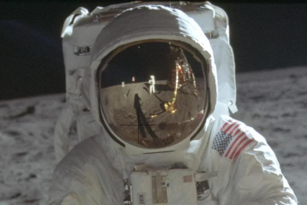 نیل آرمسترانگ فضانورد را نشان می دهد که در گیره کلاه باز آلدرین روی سطح ماه منعکس شده است.